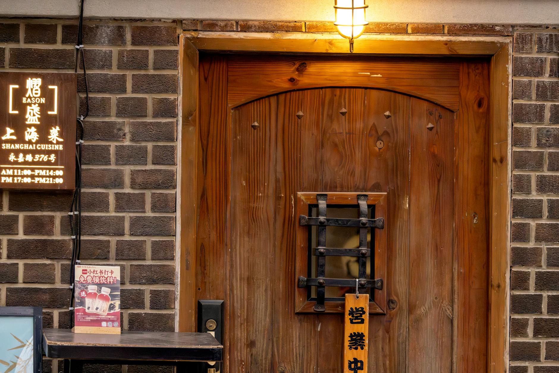 Warmly lit wooden door entrance of a Shanghai cuisine restaurant with vintage signage.