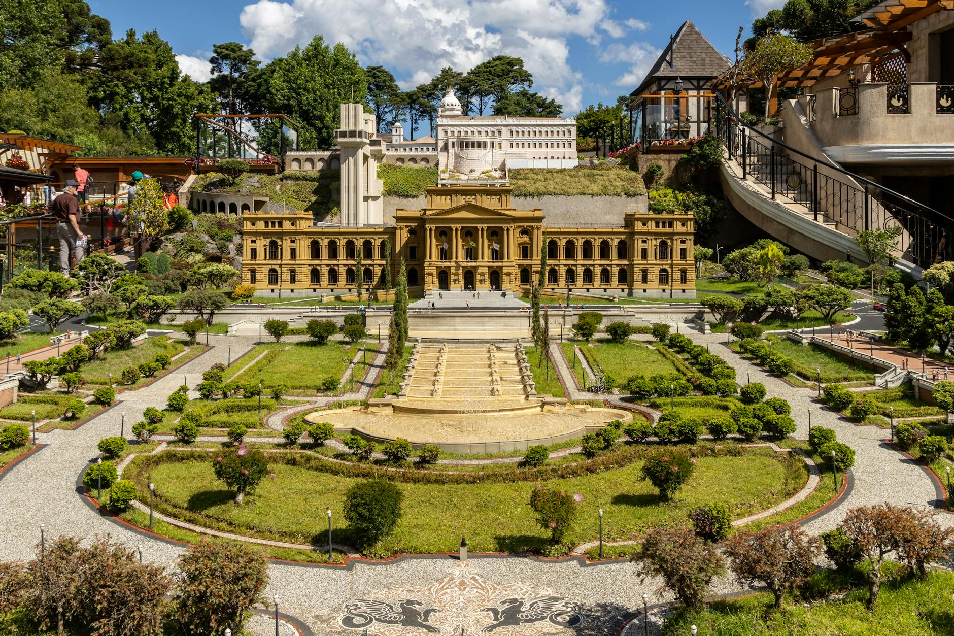 Miniature cityscape with architectural models in a sunlit park setting, showcasing intricate details.