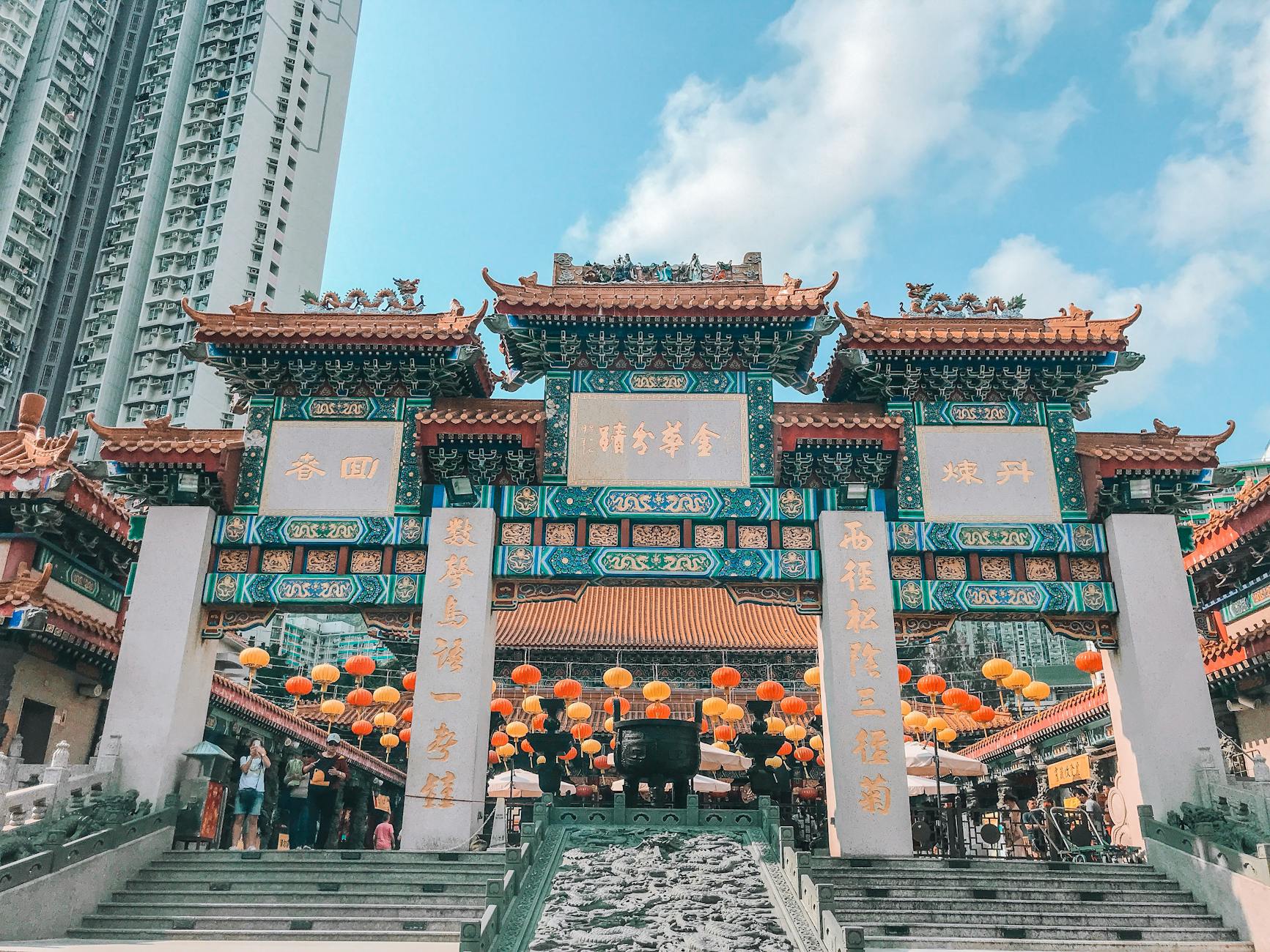 Vibrant Chinese architecture at Wong Tai Sin Temple in Hong Kong with lanterns and people.
