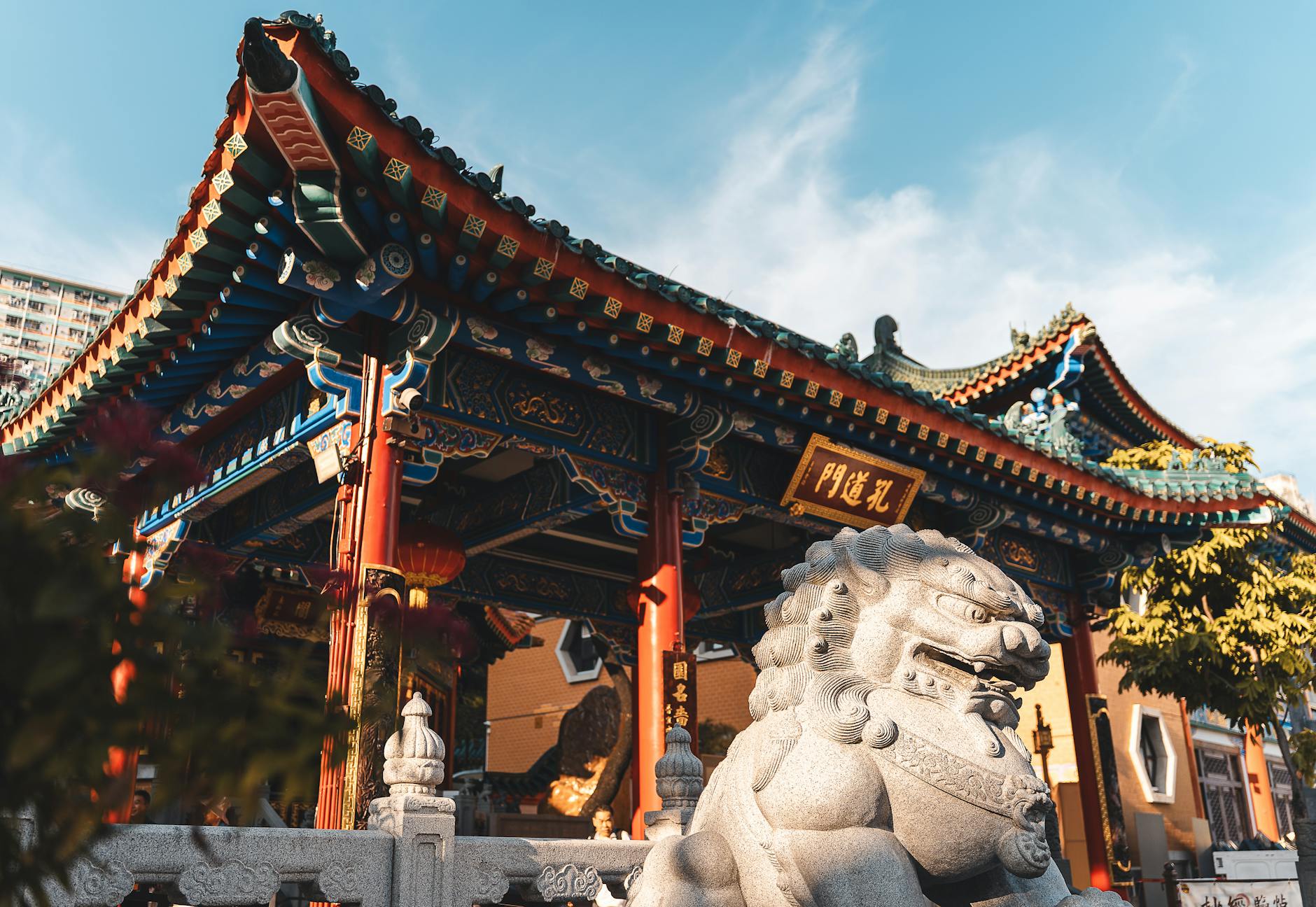 Captivating view of a traditional Chinese temple with lion statue in vibrant Hong Kong.