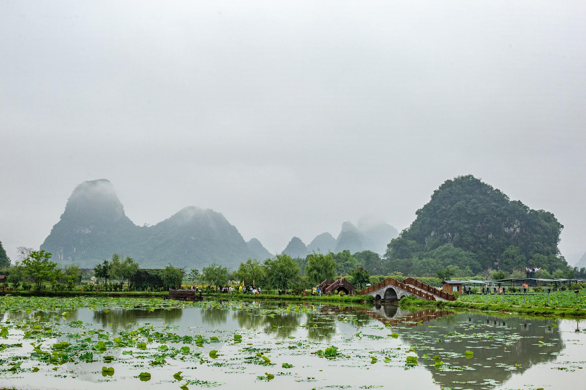 Misty landscape featuring karst hills, lush greenery, and a serene reflection in calm waters. Ideal for nature and travel enthusiasts.