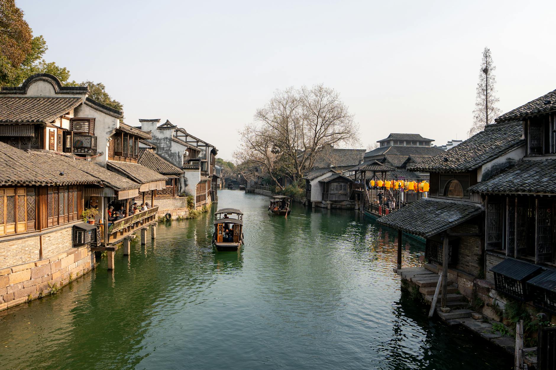 Picturesque canal scene in Wuzhen, China with traditional buildings and boats at sunset.