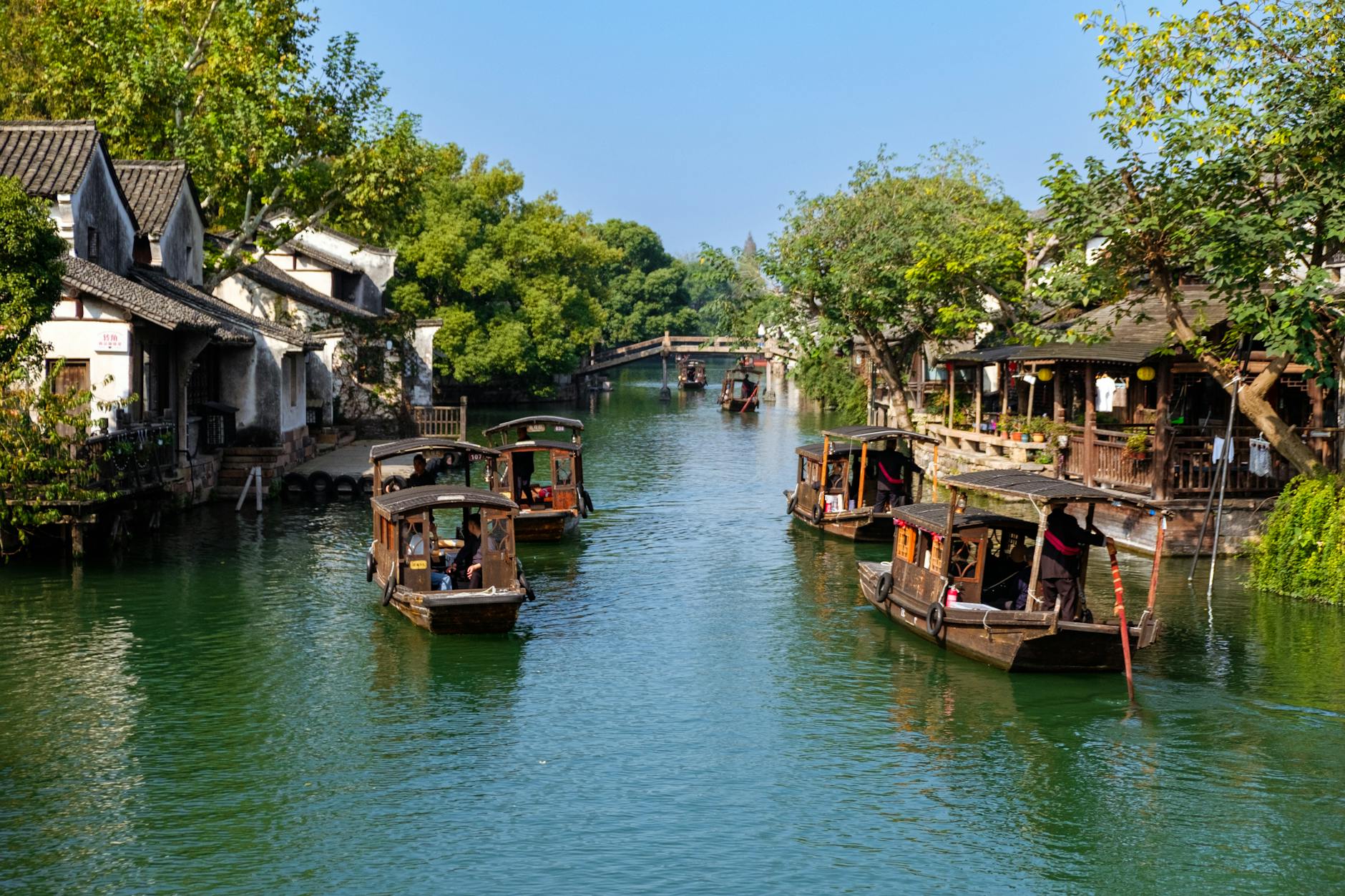 Charming scene of traditional boats navigating a peaceful river in Wuzhen, China, surrounded by historic architecture.