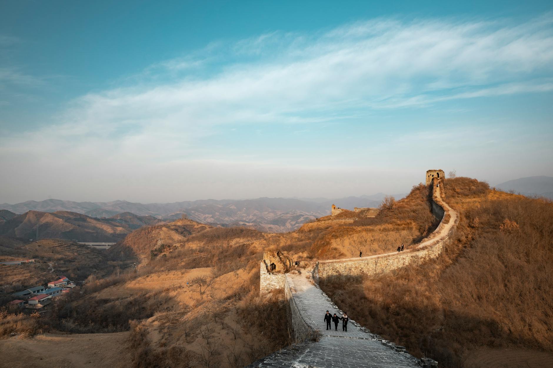 A scenic view of the Great Wall of China stretching across the rugged landscape under a clear blue sky.