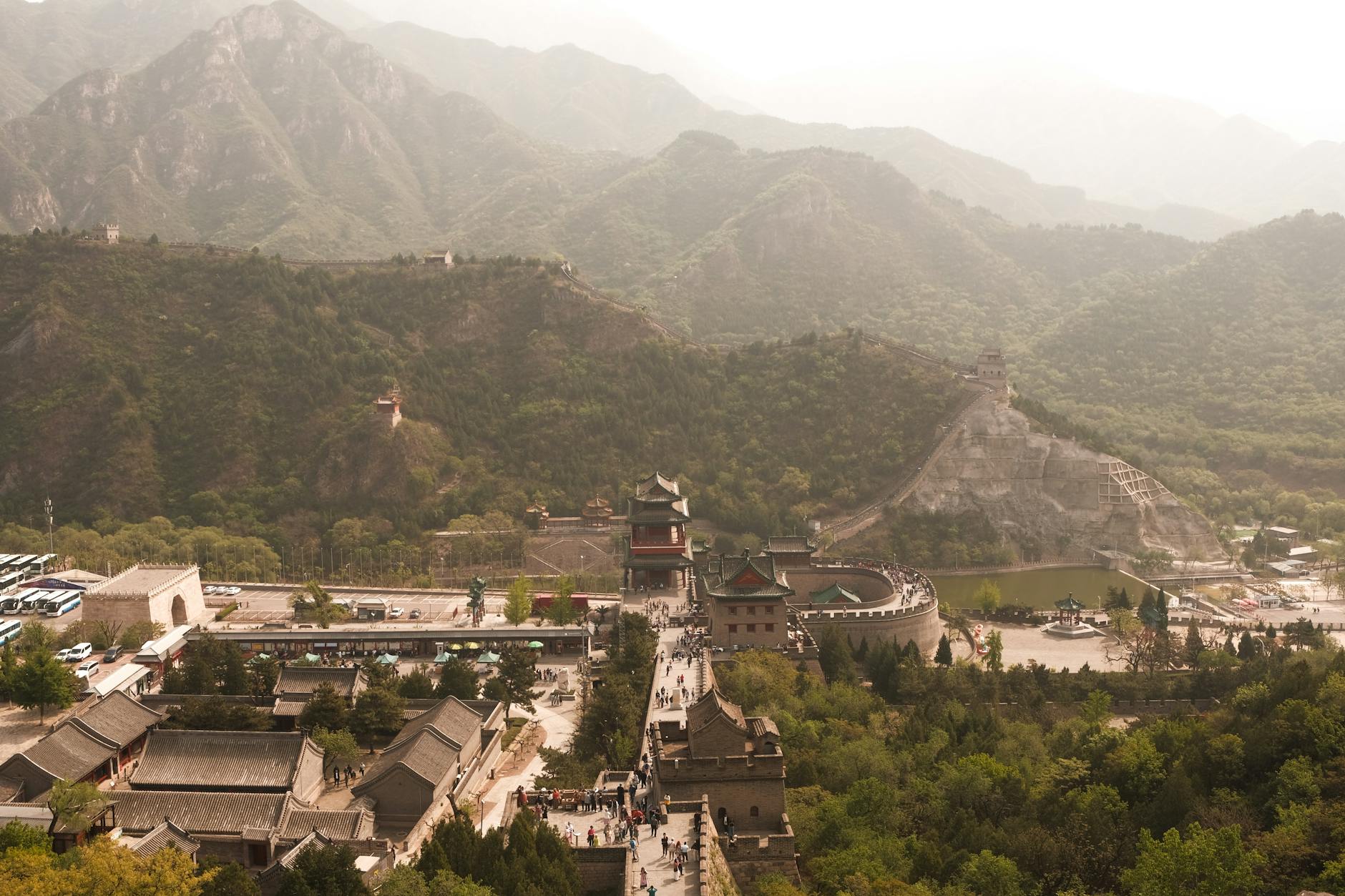 A scenic aerial view of the Great Wall of China surrounded by lush mountains in spring.