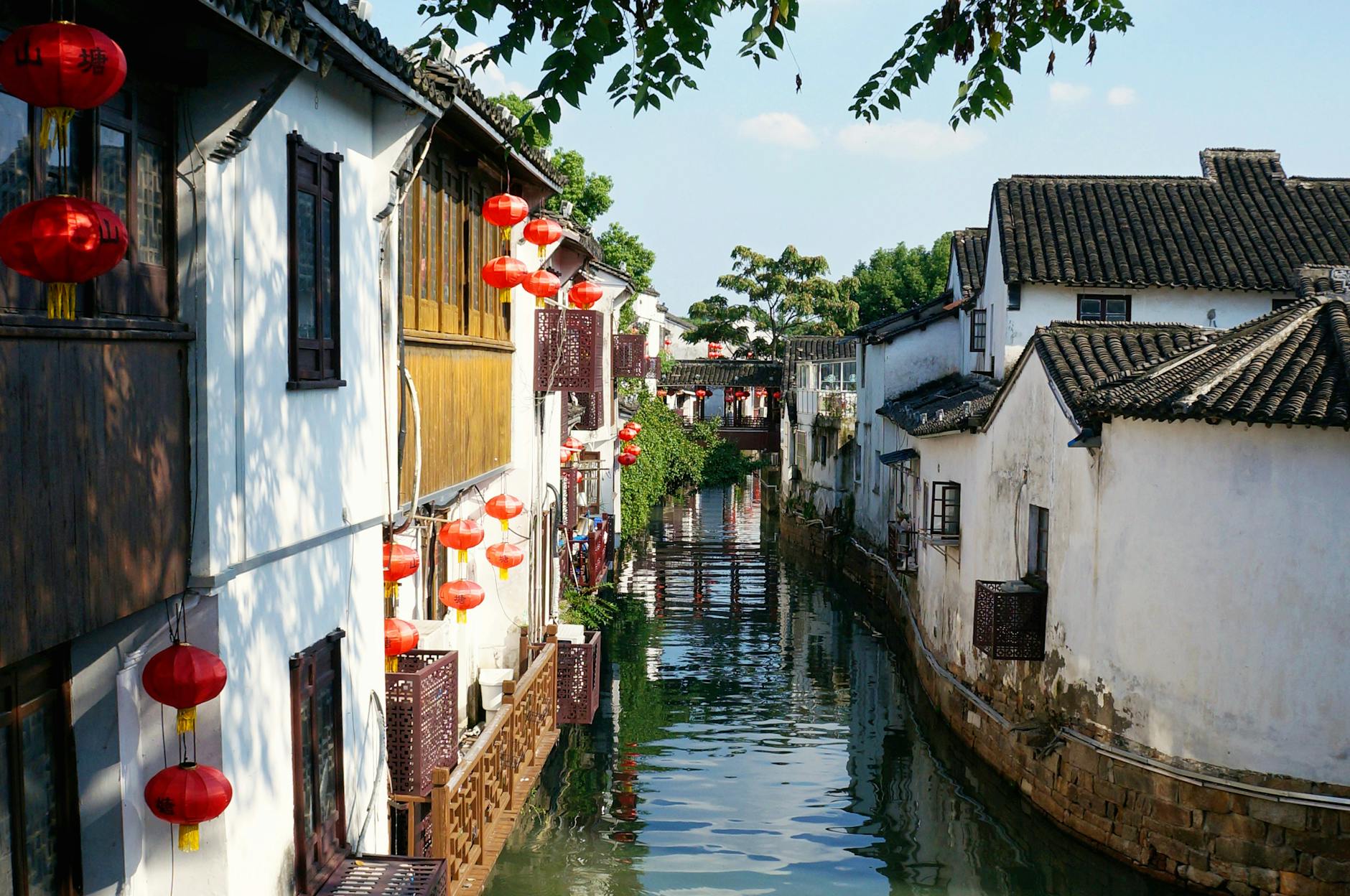 Scenic view of a historic Chinese water town featuring traditional architecture and vibrant red lanterns.