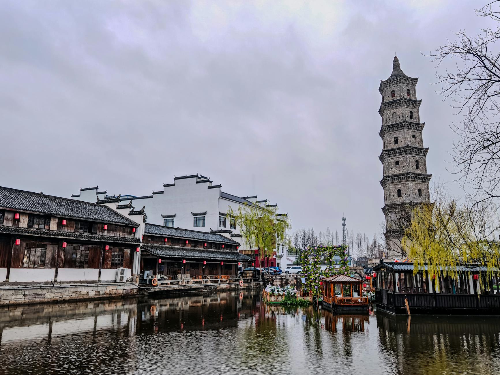 A scenic view of a traditional Chinese pagoda beside a serene canal with architectural charm.