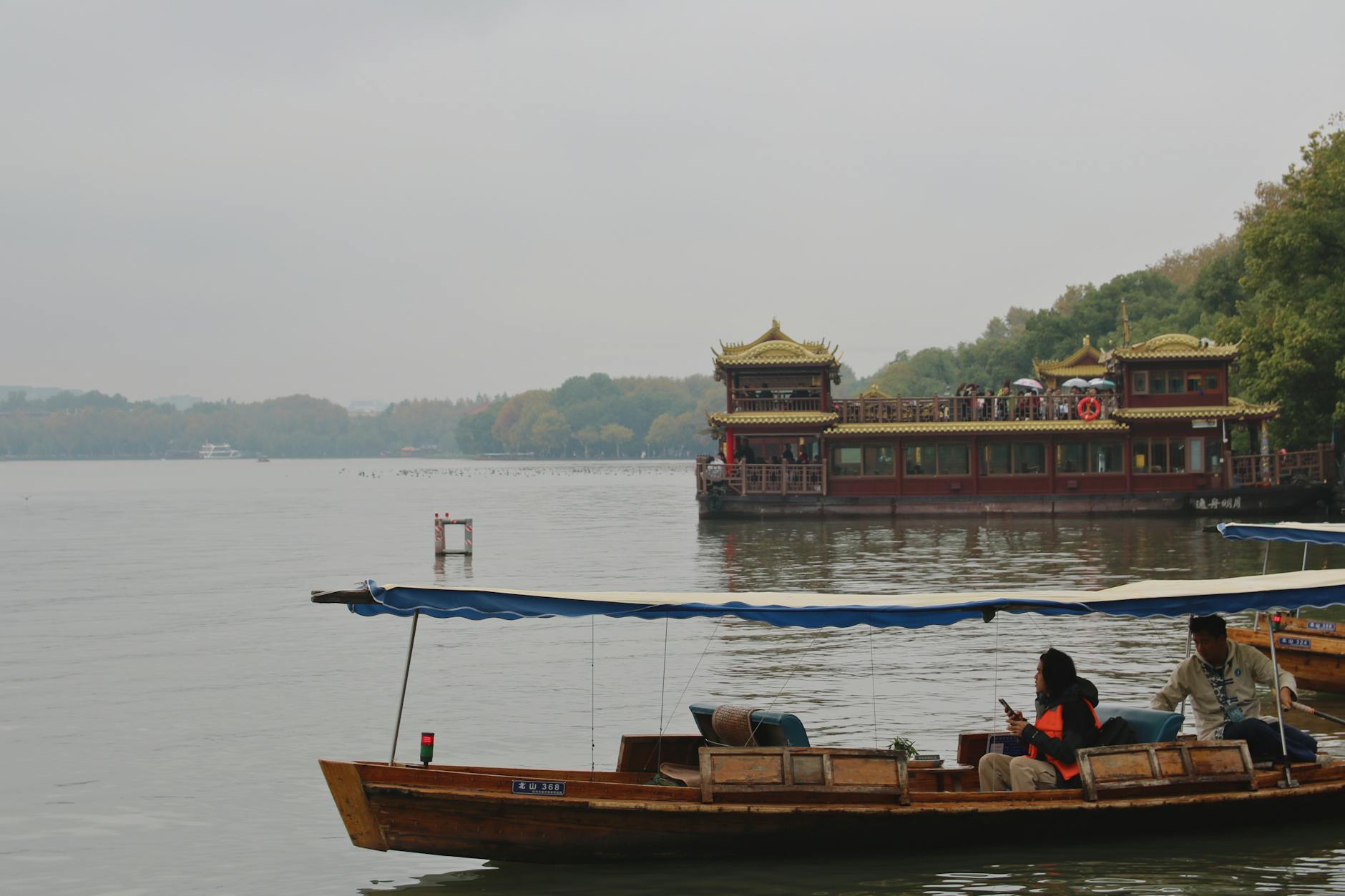 Picturesque view of West Lake in Hangzhou with a traditional Chinese boat and pagoda. Tranquil autumn setting.