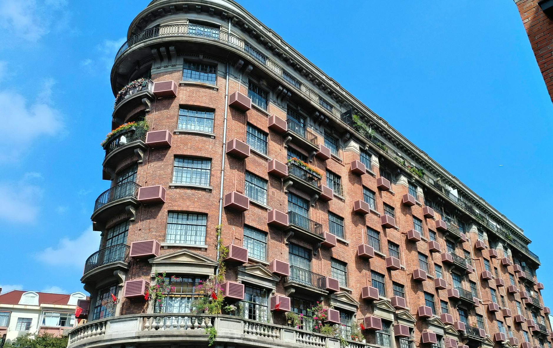 Elegant red-brick apartment building with blue sky background, showcasing classic architectural design.