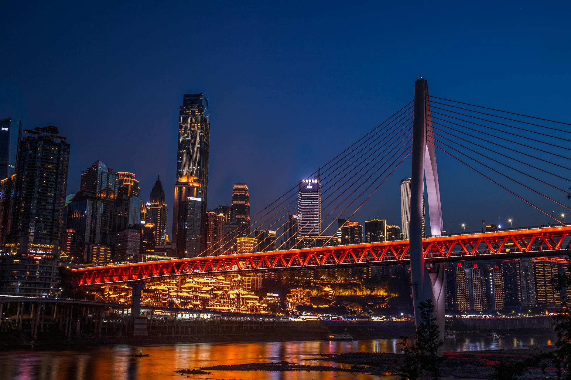 Stunning nighttime view of Chongqing city with illuminated skyscrapers and iconic bridge.