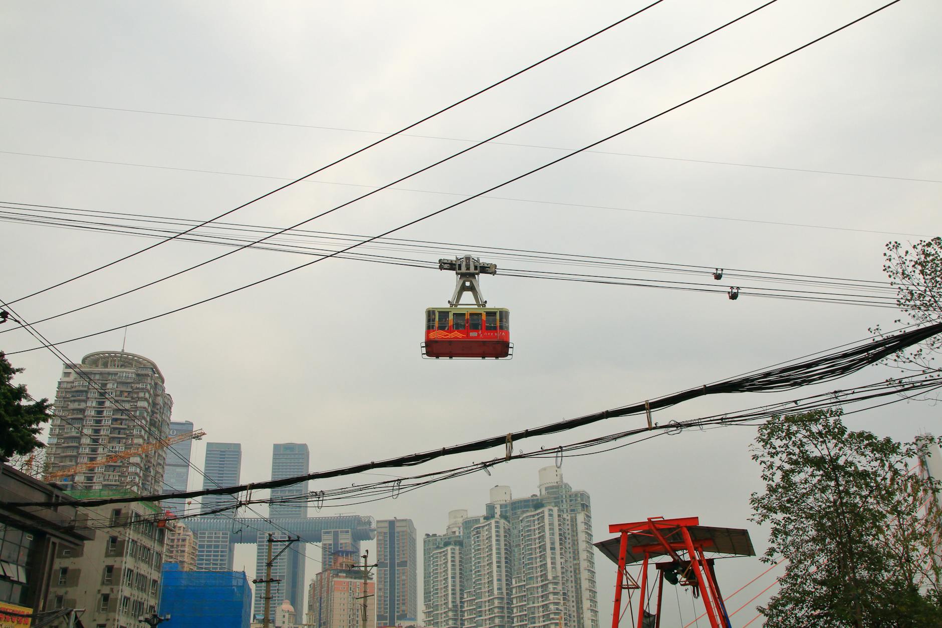 Cable car crossing over Chongqing skyline, showcasing urban architecture and transport.