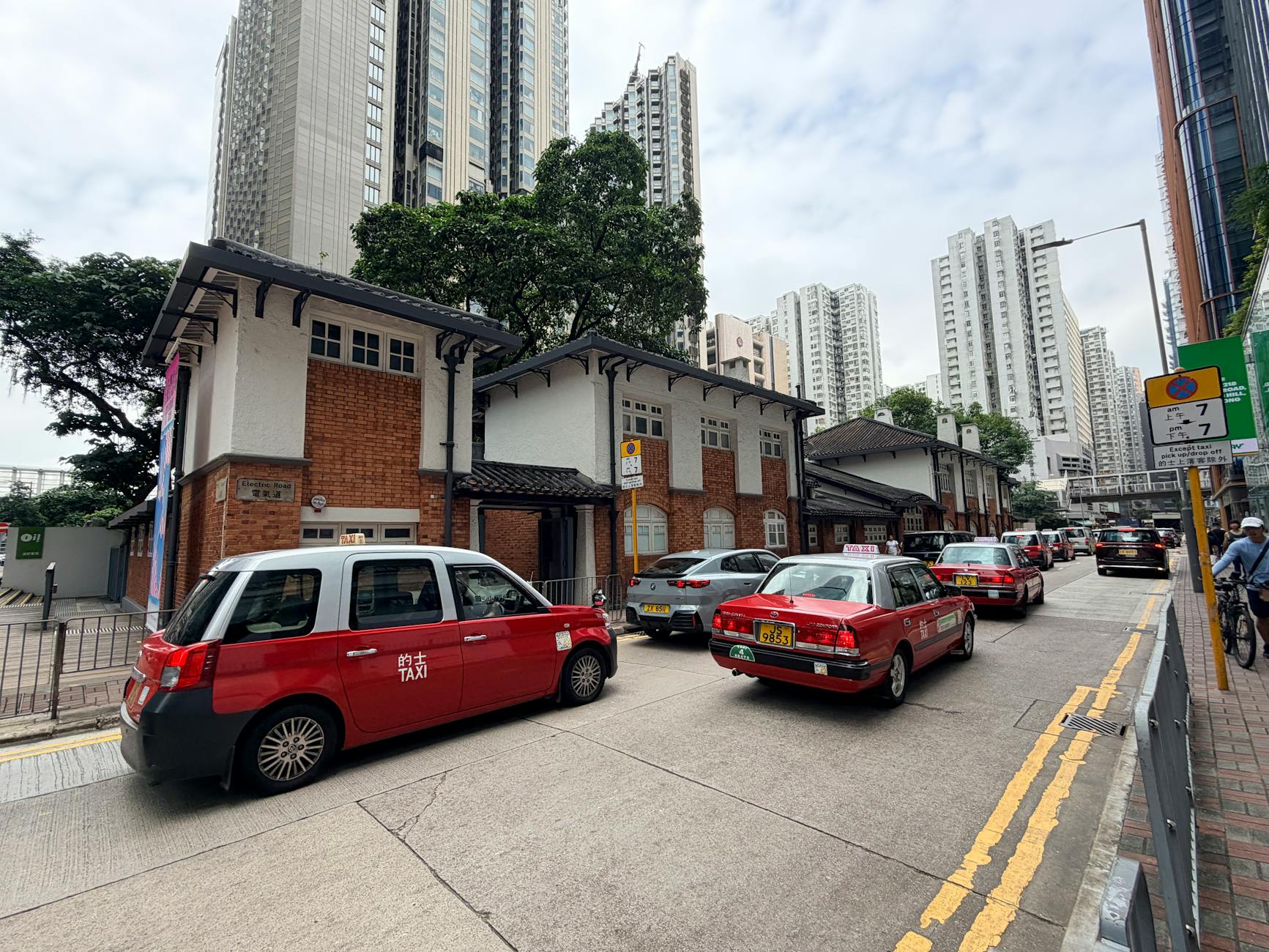 Red taxis line the street in Hong Kong, blending modern skyscrapers with classic architecture.
