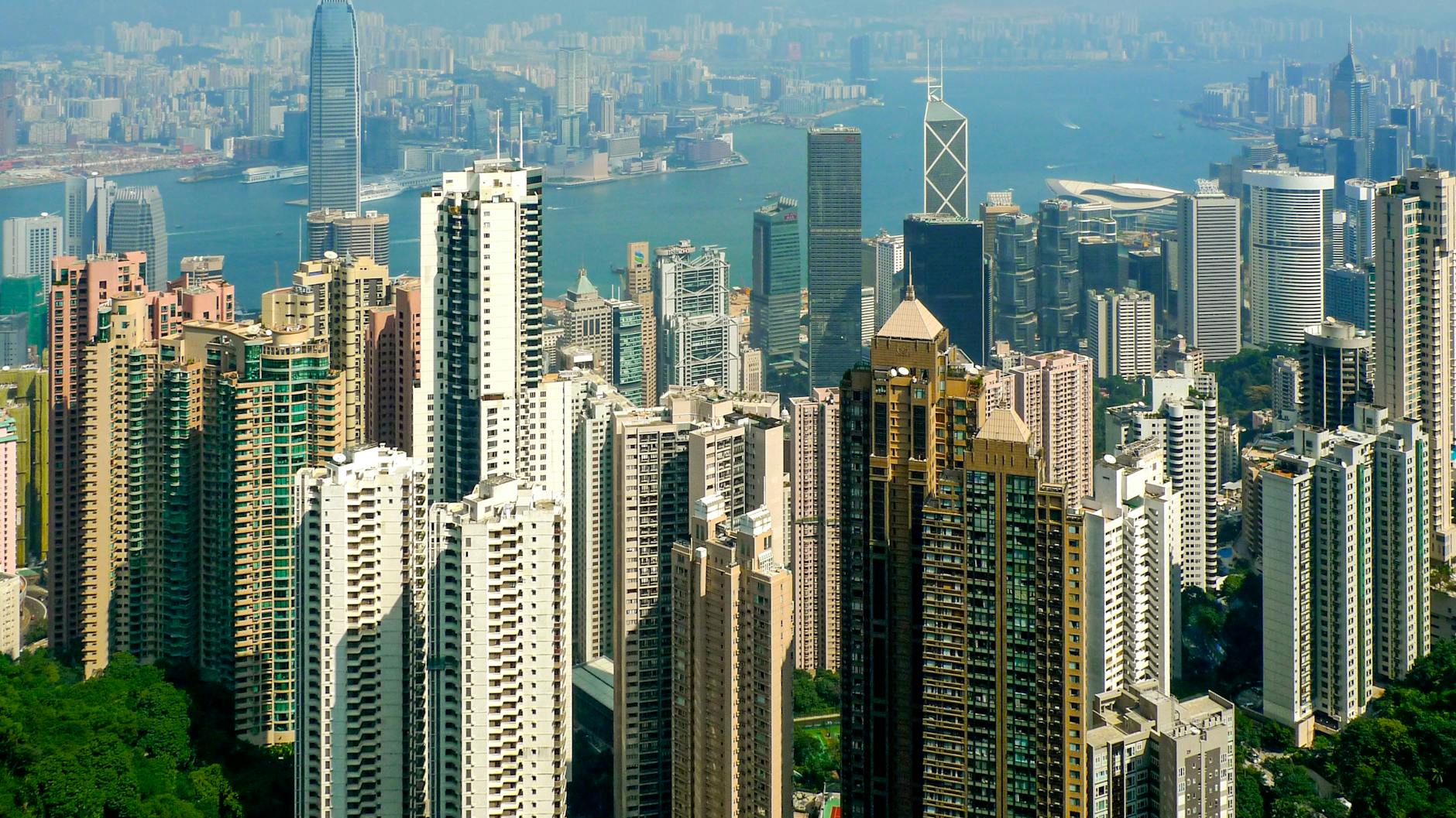 Panoramic view of skyscrapers on Hong Kong Island with Victoria Harbour in the background.