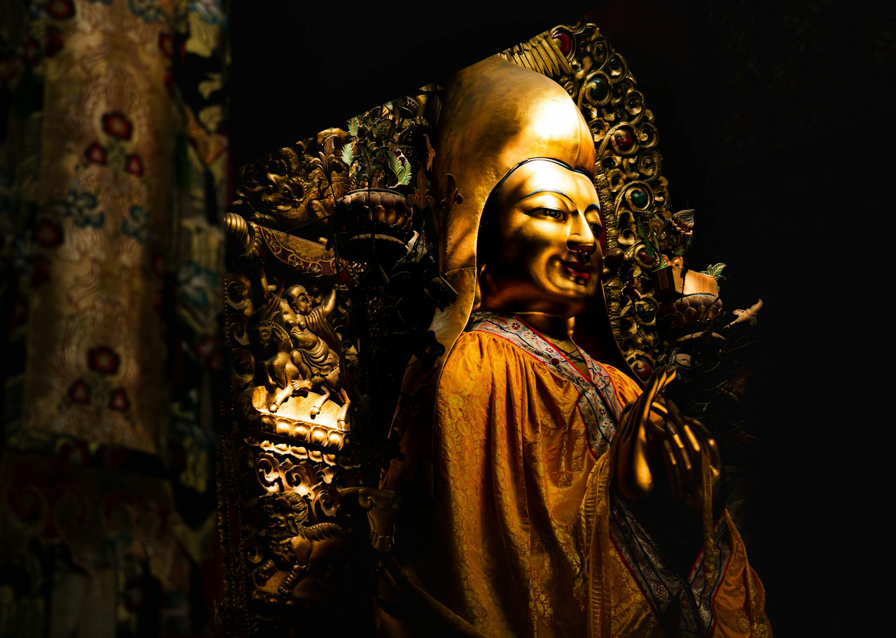 A striking golden Buddha statue inside a richly decorated Chinese temple in Beijing.