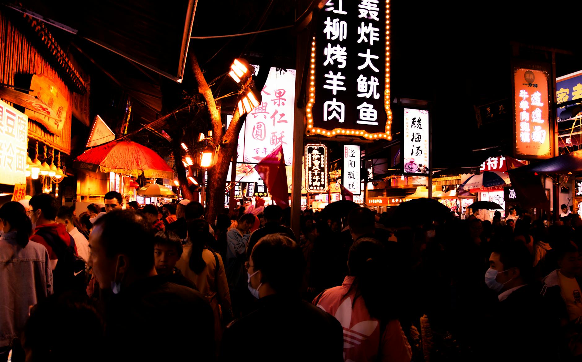 Bustling night market in Xi'an, Shaanxi, featuring illuminated signs and a lively crowd.