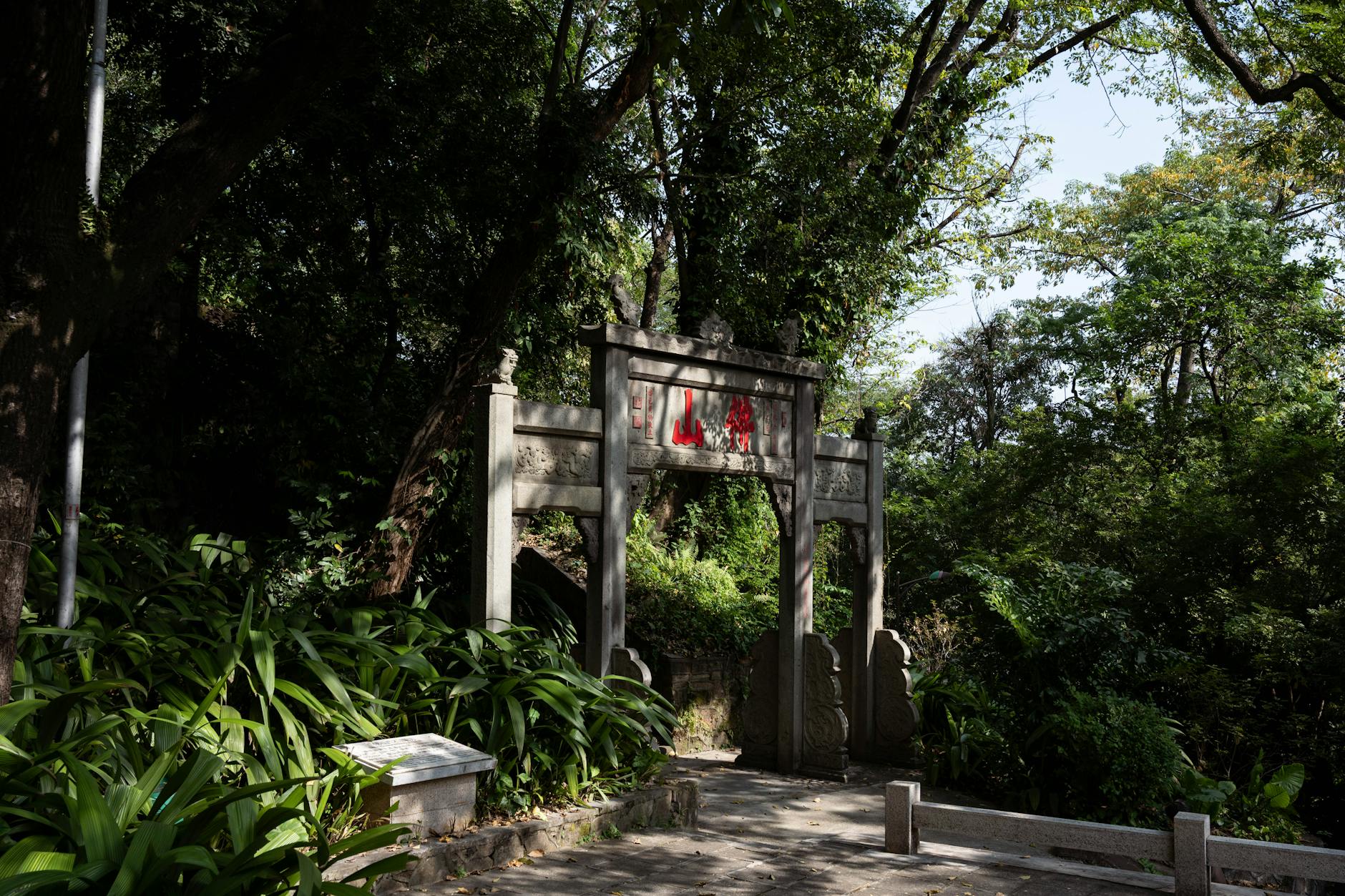 An ancient stone gate surrounded by lush greenery in a peaceful forest setting in Guangzhou, China.