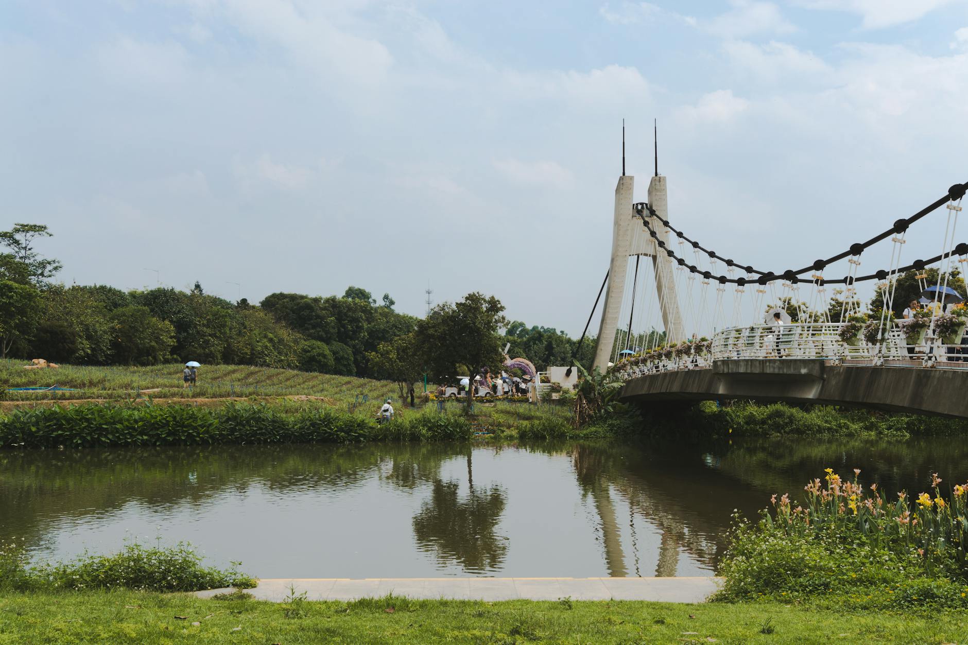 A serene landscape featuring a suspension bridge over a river with lush greenery in Guangzhou, China.