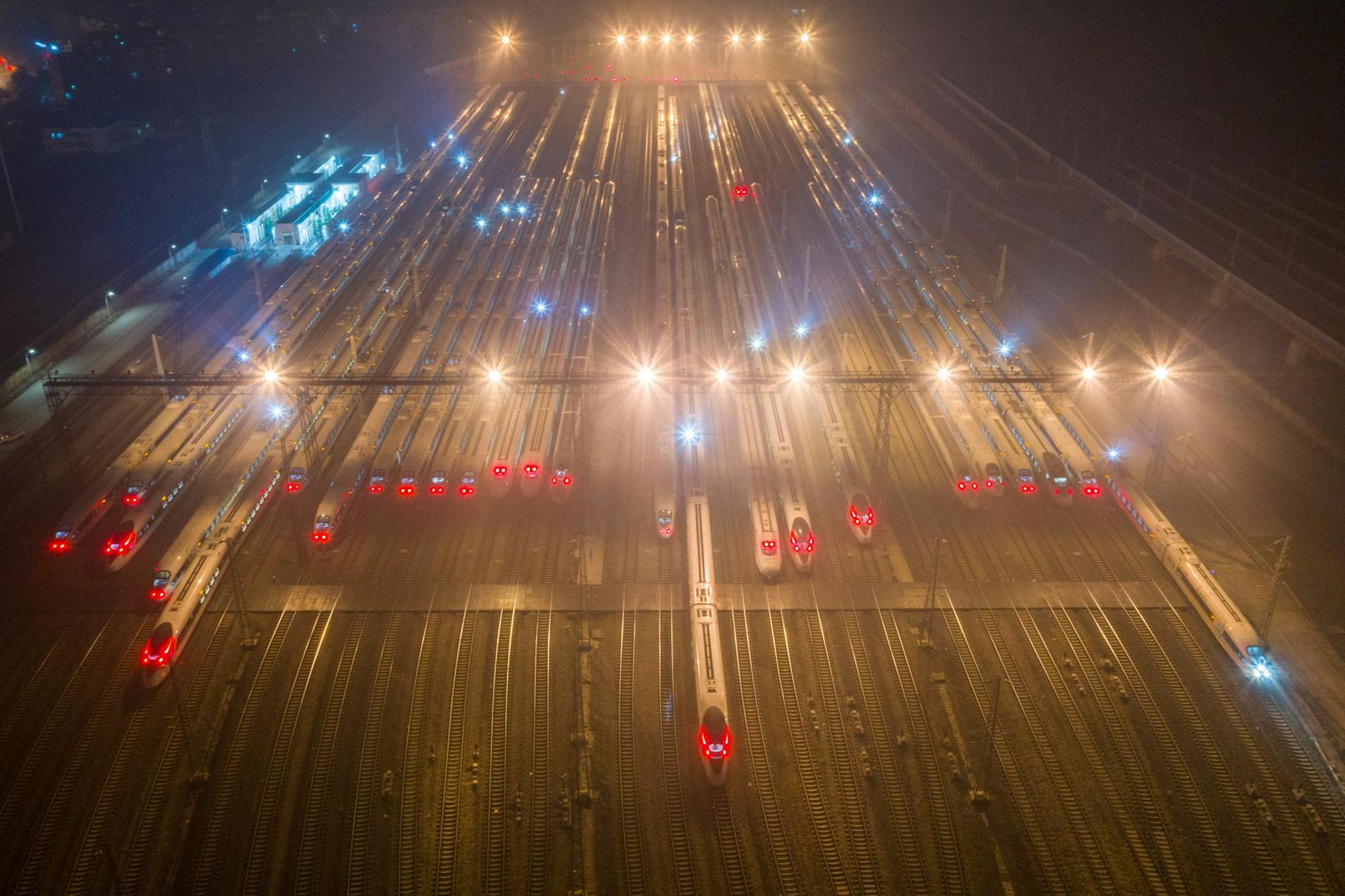 A nighttime aerial view of trains at an illuminated railway station in Nanjing, China.