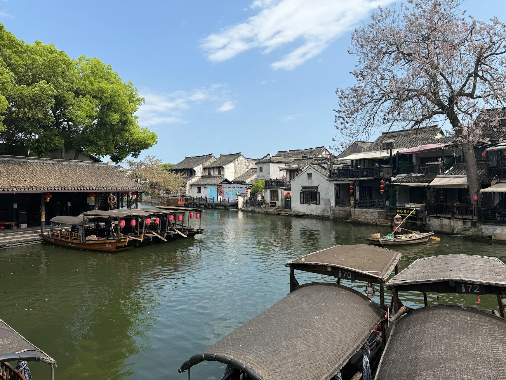 Peaceful view of a traditional Chinese water town with boats and historic architecture.
