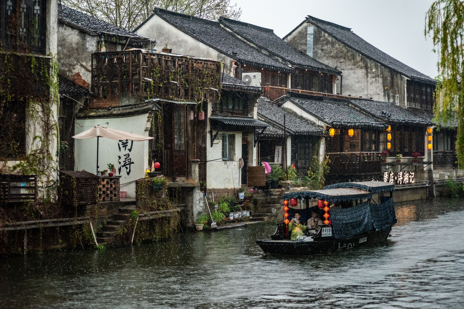 Beautiful canal with a boat and traditional Chinese houses in a serene setting.