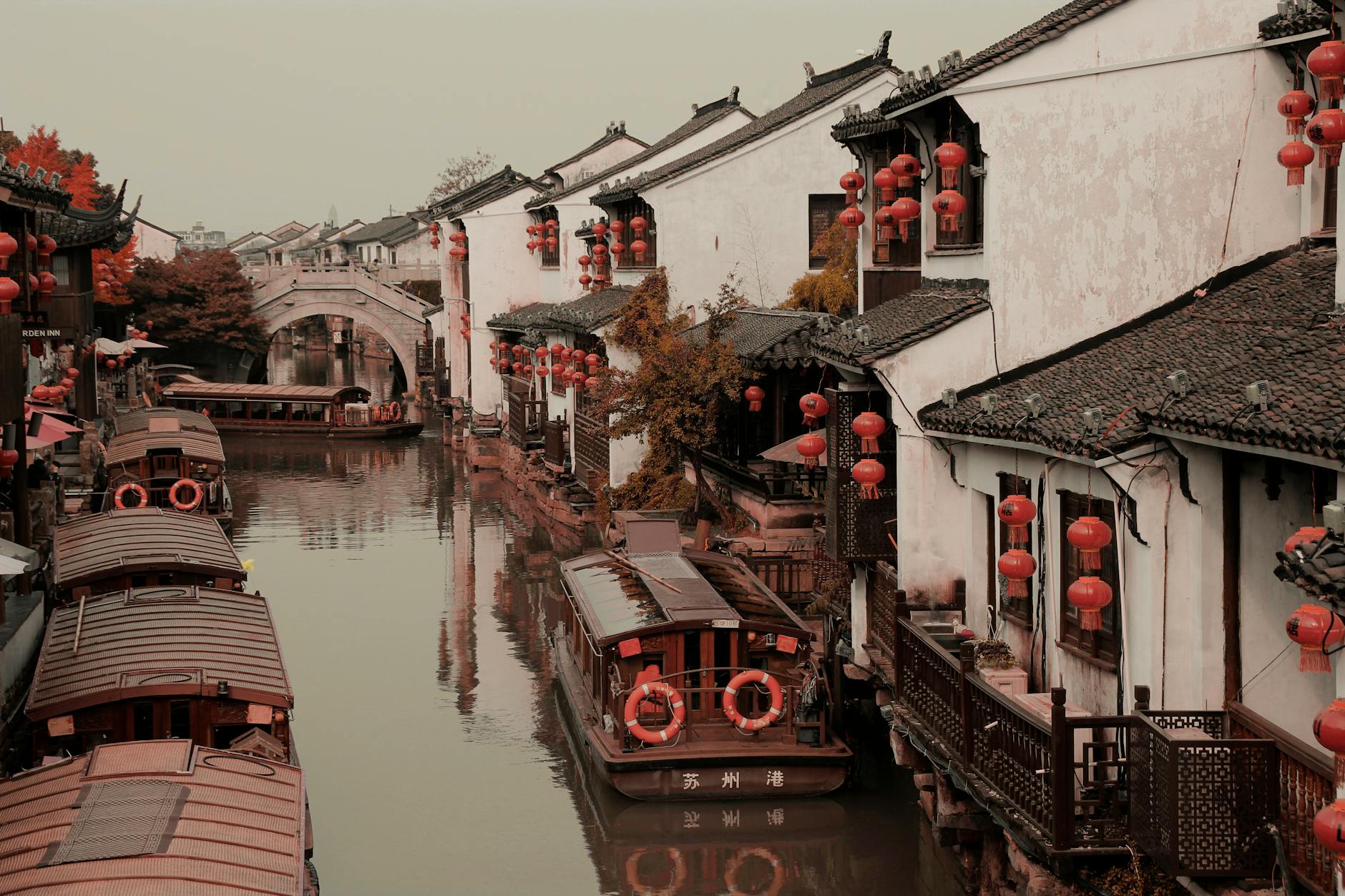 Beautiful canal in Suzhou, China, adorned with red lanterns and traditional boats, showcasing serene reflections.