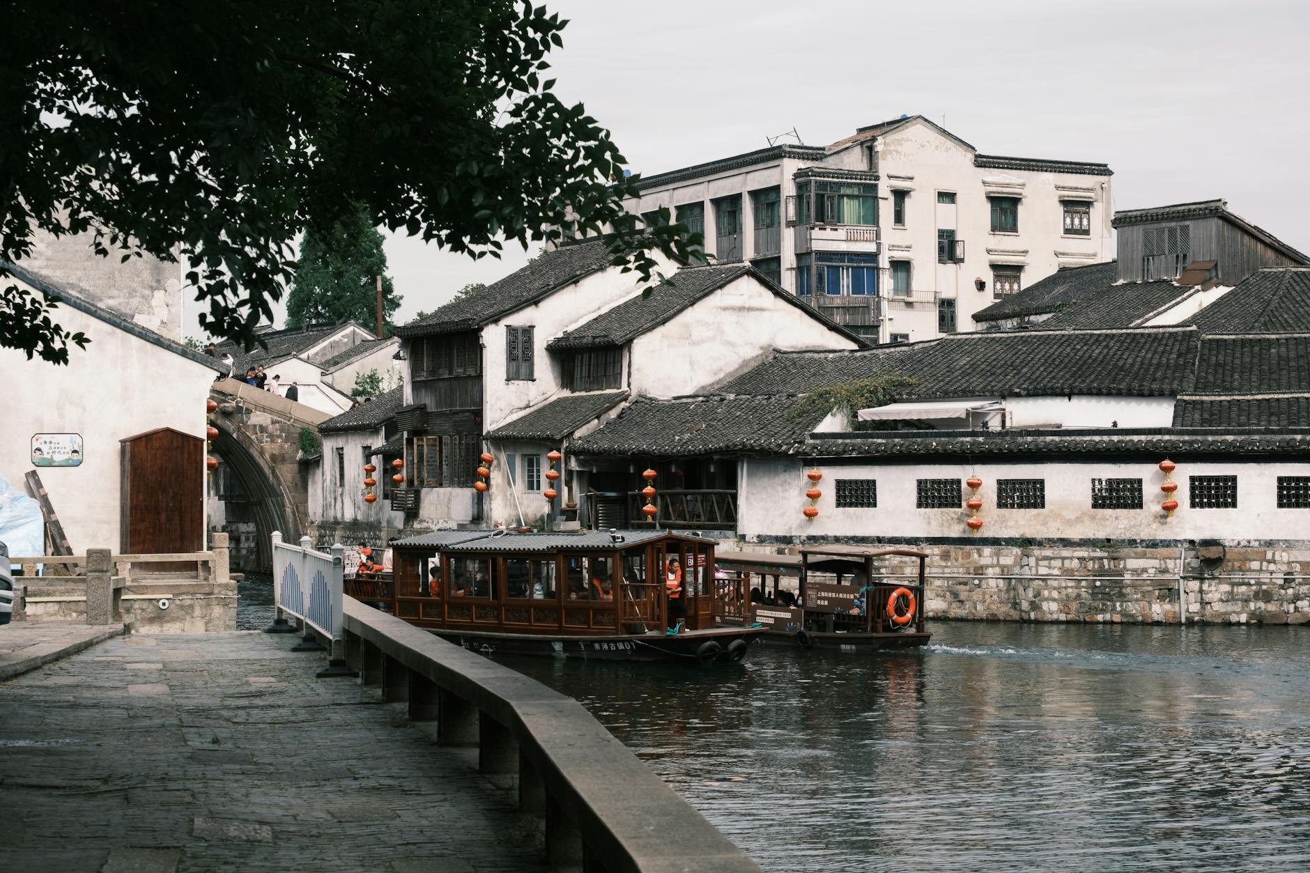 Serene canal scene in a historic Asian town with traditional boats and architecture.