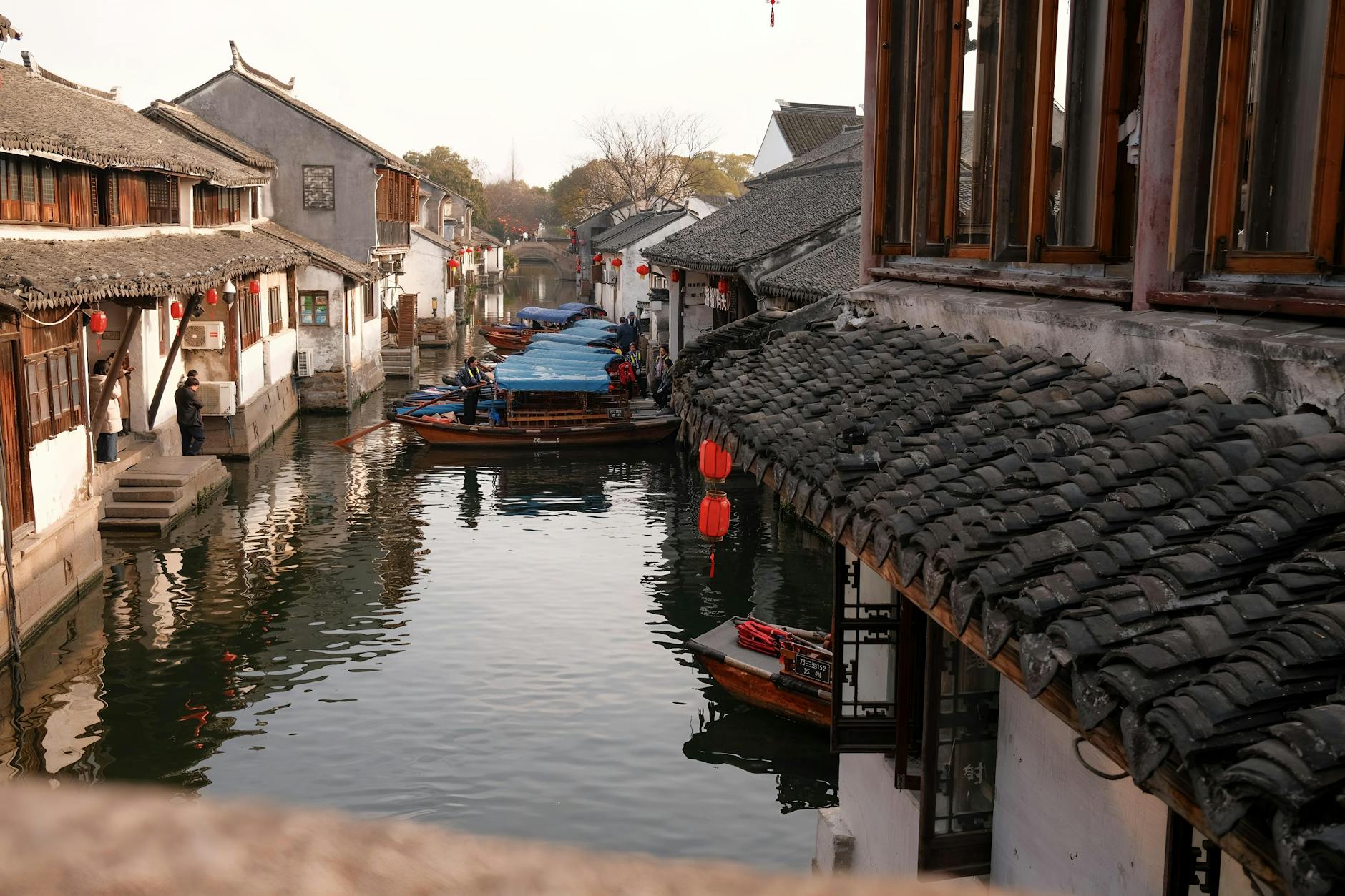 Peaceful view of historic canal in Suzhou, showcasing traditional architecture and boats.