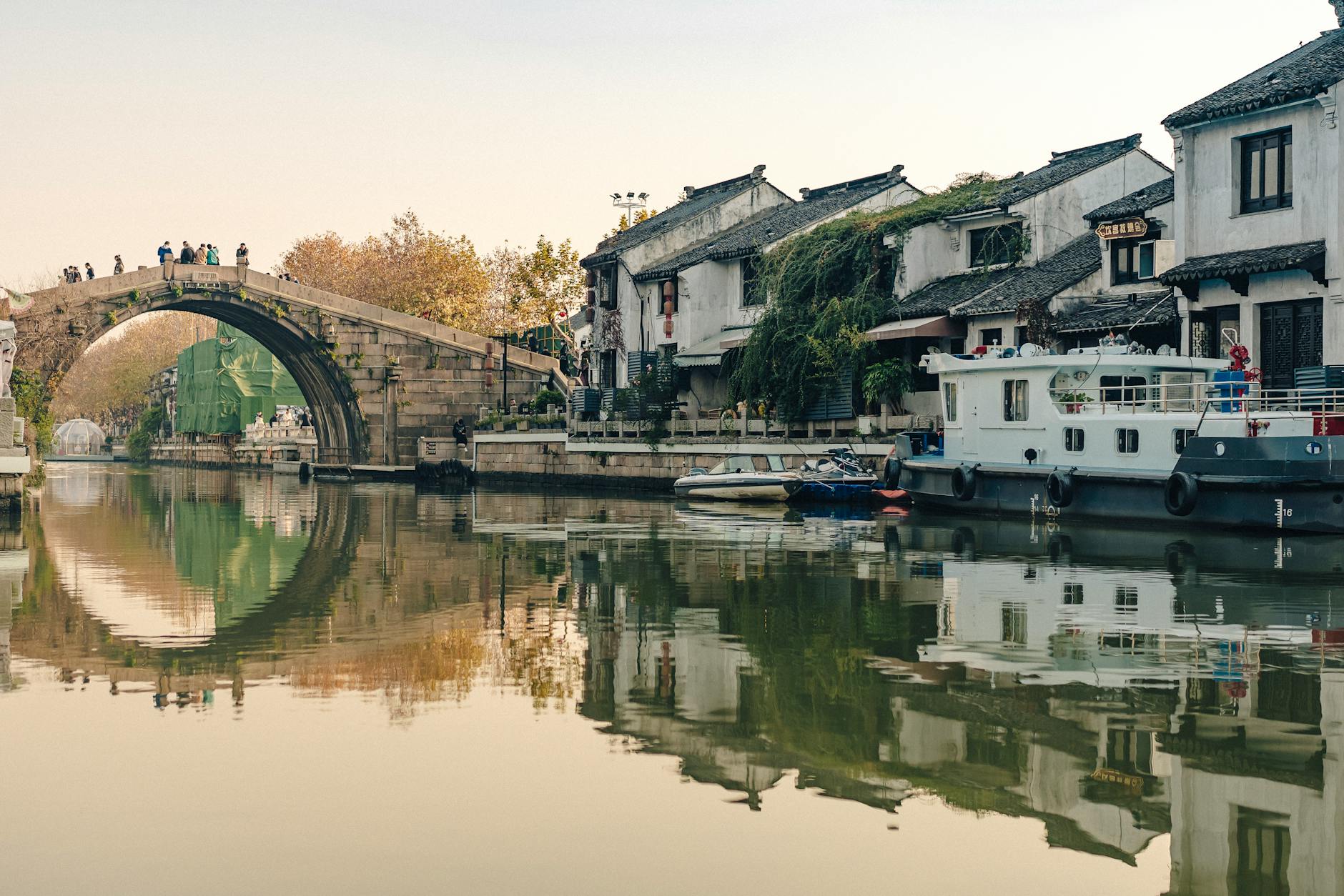 Picturesque canal with historic bridge and traditional houses reflecting in the water.